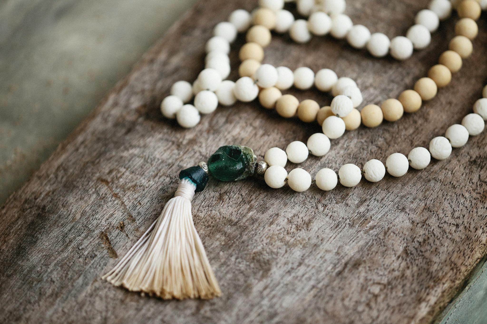 Close-up of vintage prayer beads with a tassel on a wooden surface, evoking tranquility.